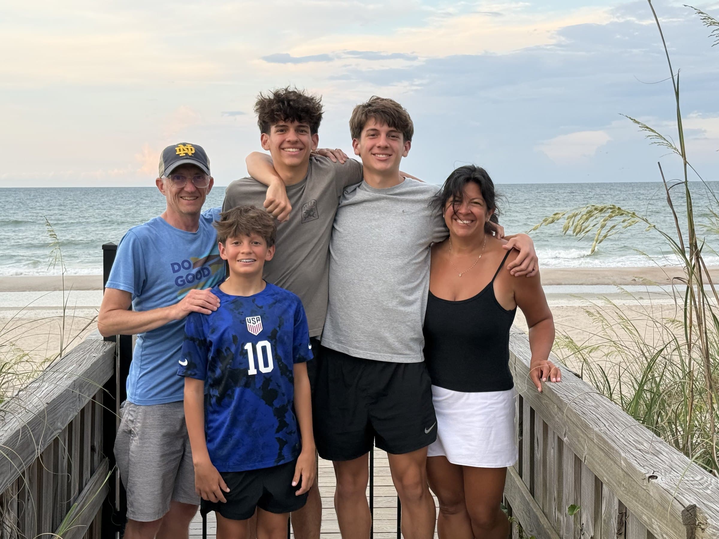 Zach, Melanie, and their three boys on a beach walkway at dusk.